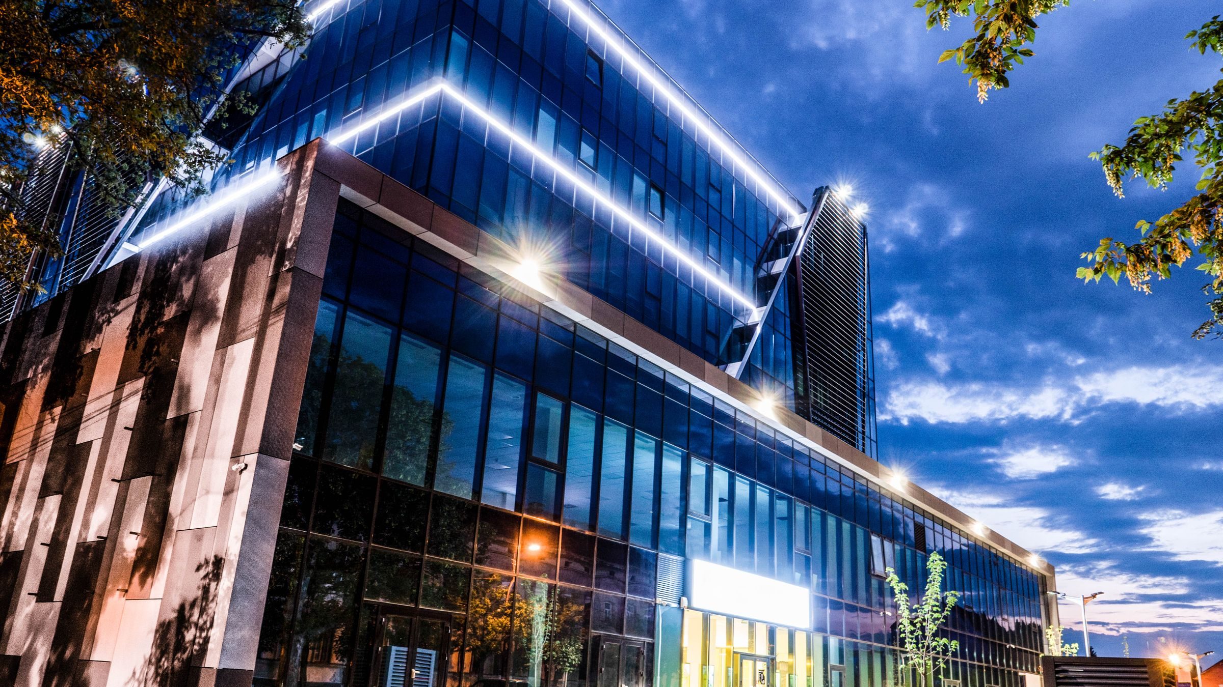 A modern office building lit at dusk