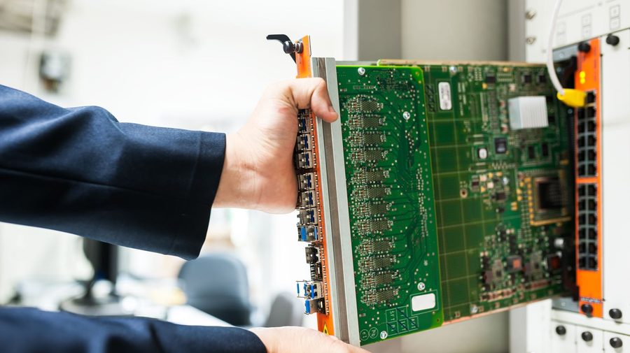 A hand seating a card into hardware